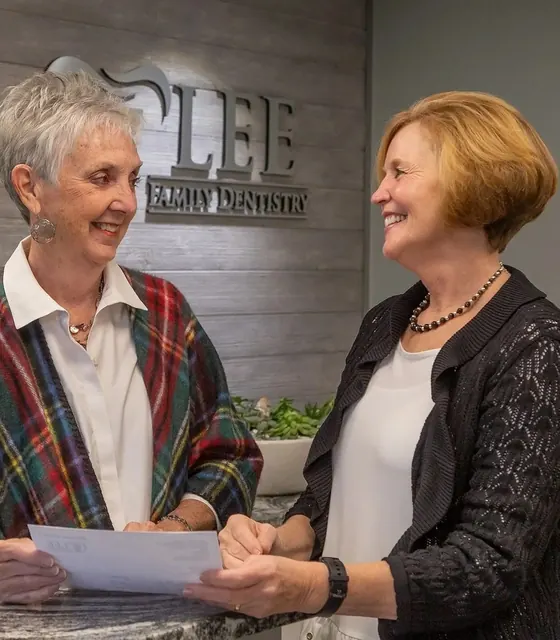 A patient and a team member going over paperwork at the front desk.