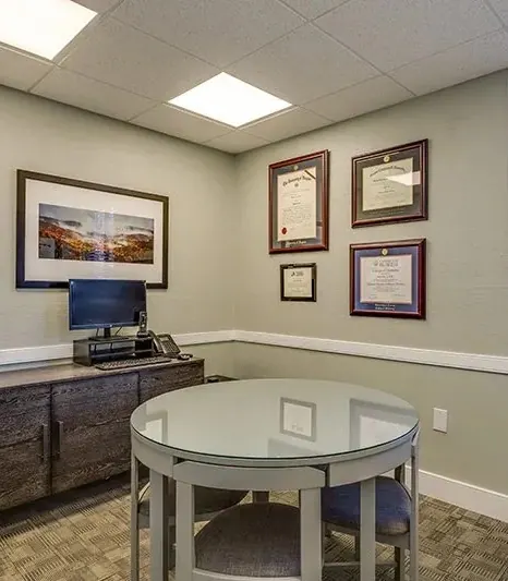 The consultation office, with a round glass table and framed diplomas.
