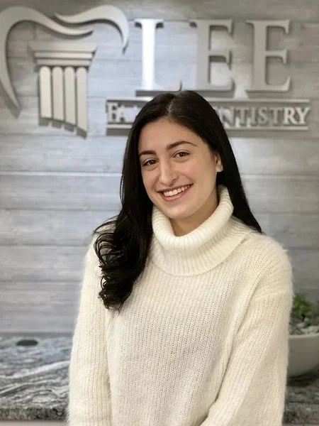 Amber, of the Lee Family Dentistry team, in front of the office sign.