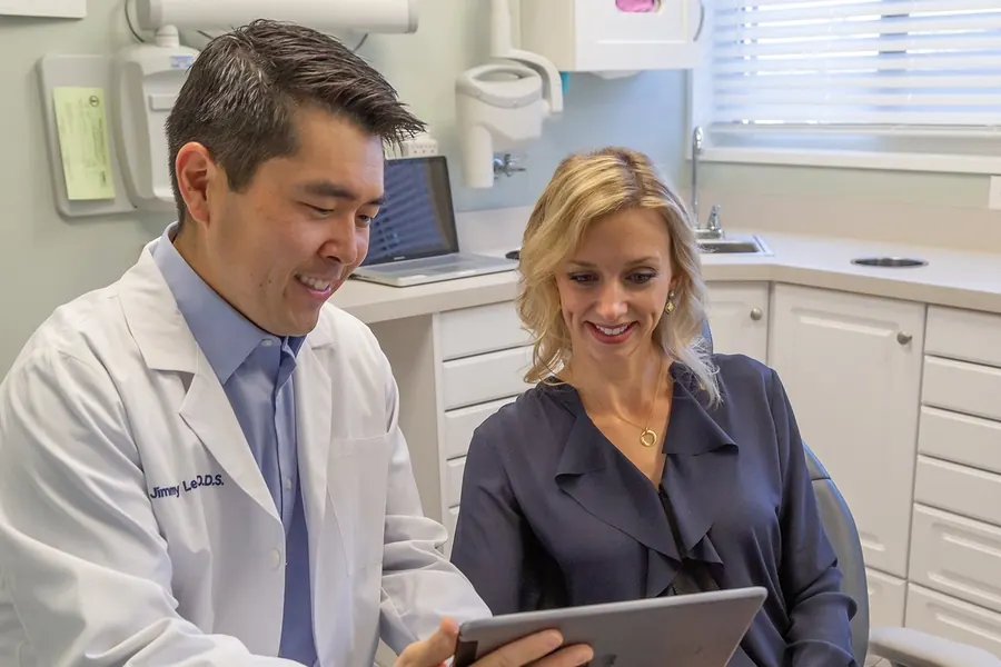 Dr. Jimmy Lee showing a patient her dental images on an iPad in a treatment room.